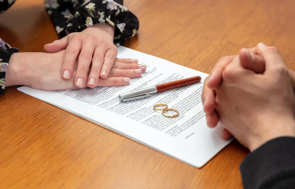 Mãos sobre documento com anéis e caneta, indicando consulta com advogado de família.