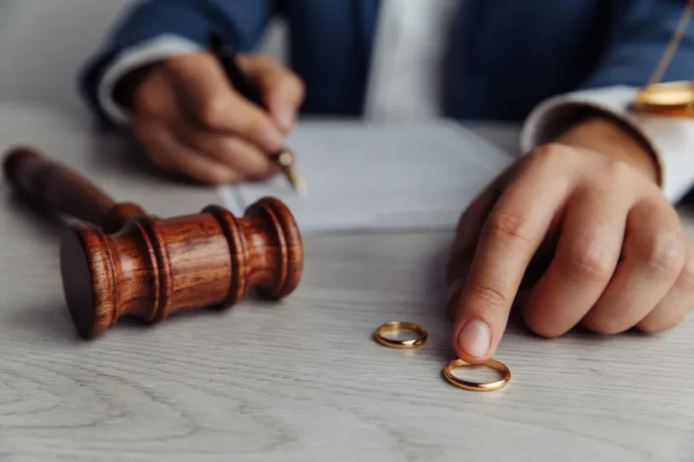 Martelo de juiz, anéis e mão em processo de divórcio com bens e sem filhos.