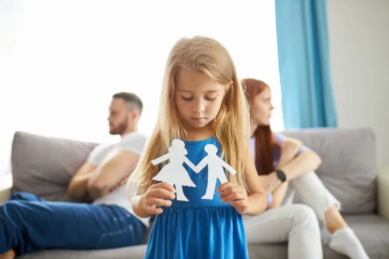 Menina segura recortes de papel representando pais, simbolizando divórcio com filhos menores.