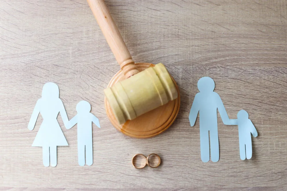 Martelo de juiz simboliza divórcio com filhos menores e anéis de casamento.