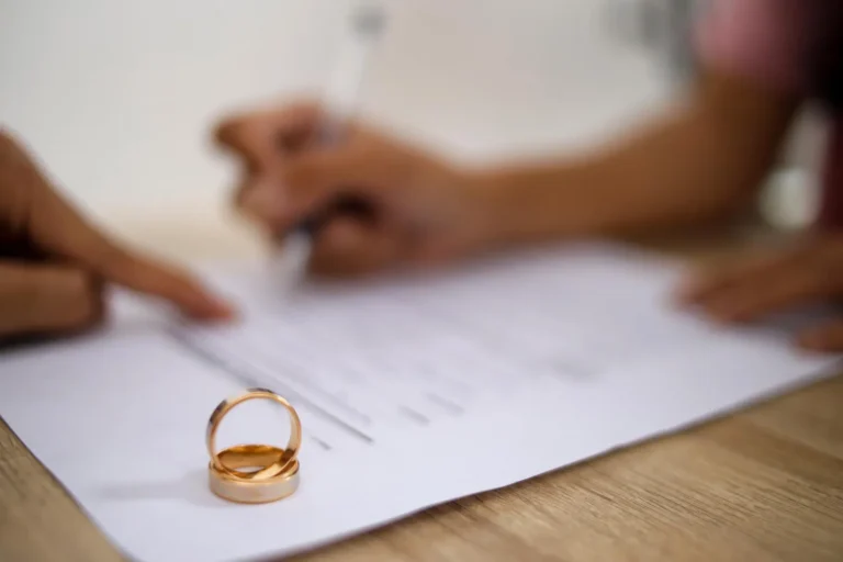 Anéis de casamento em papel com assinatura, indicando divórcio com violência doméstica.
