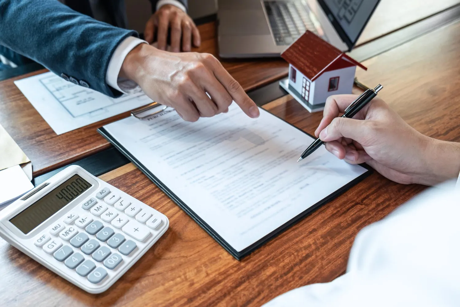Assinatura de contrato com calculadora e modelo de casa, explicando inventário negativo o que é.