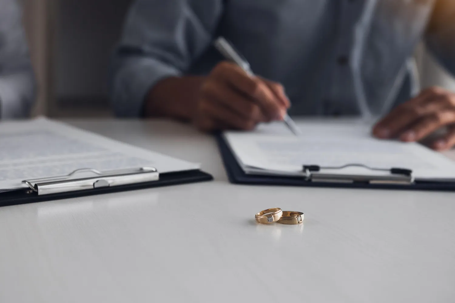 Anéis de casamento e documentos sobre partilha de bens no divórcio como funciona.
