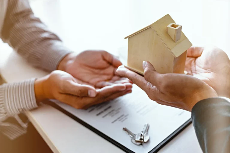 Mãos entregando miniatura de casa, discutindo quem tem direito a herança.