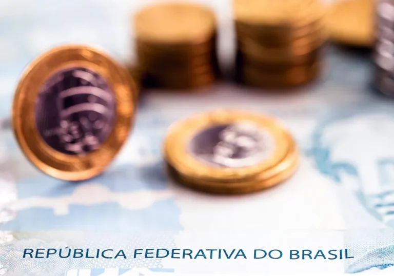 Moedas de real em cima de nota da República Federativa do Brasil, sobre até quando pagar pensão alimentícia para o filho.