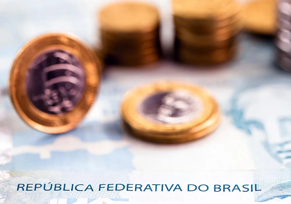 Moedas de real em cima de nota da República Federativa do Brasil, sobre até quando pagar pensão alimentícia para o filho.