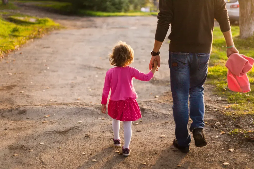 Pai e filha caminhando de mãos dadas, representando pedido de guarda compartilhada.